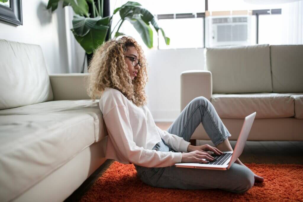 woman of color on floor against couch on laptop